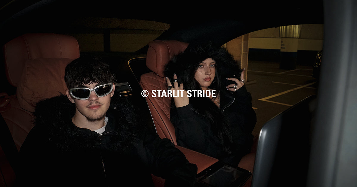 Two people sitting inside a mercedes s class at night, wearing dark clothing and sunglasses.