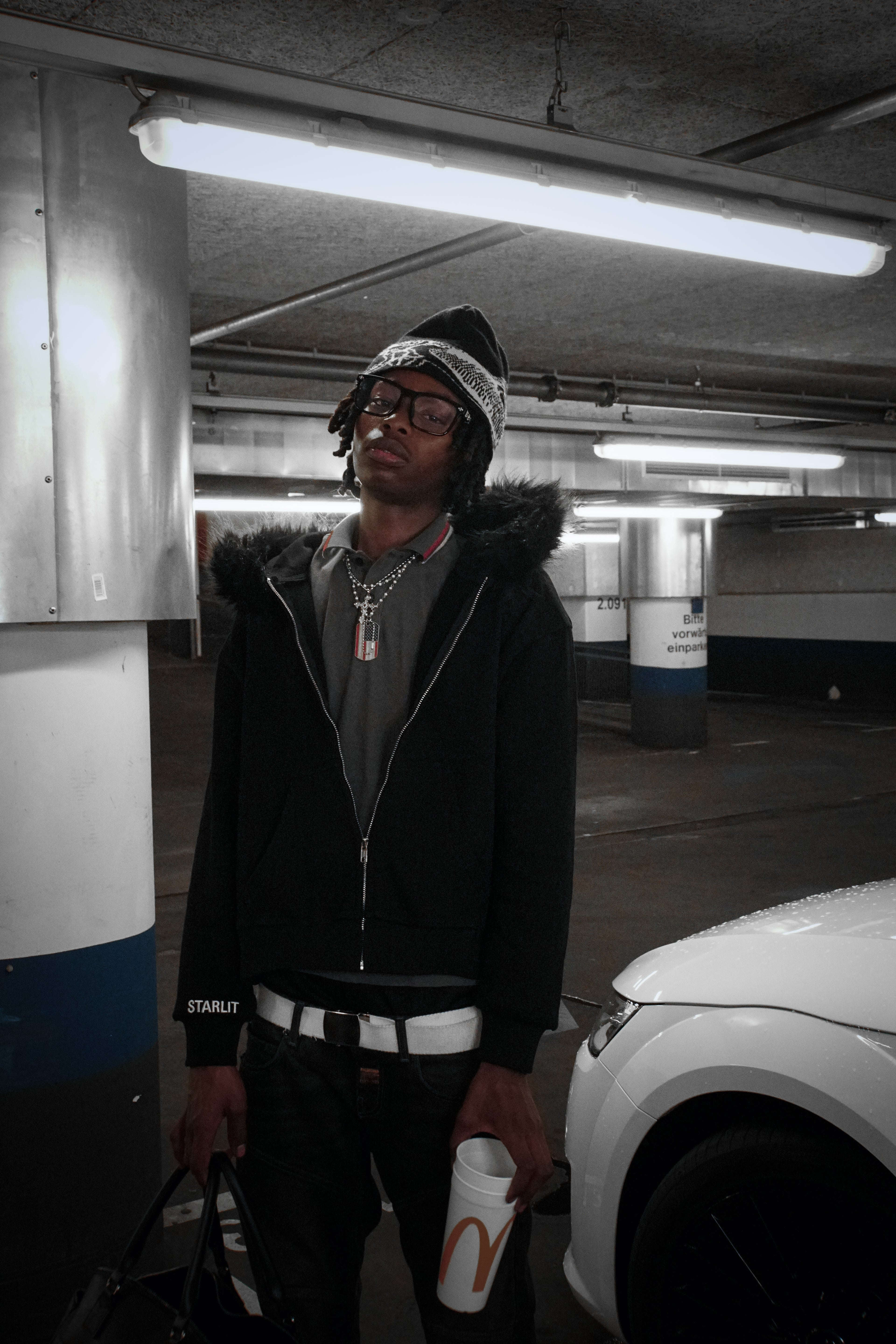 Person standing in a parking garage holding a McDonald's cup