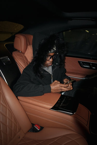 Person wearing a black outfit with fur hood in an industrial setting
