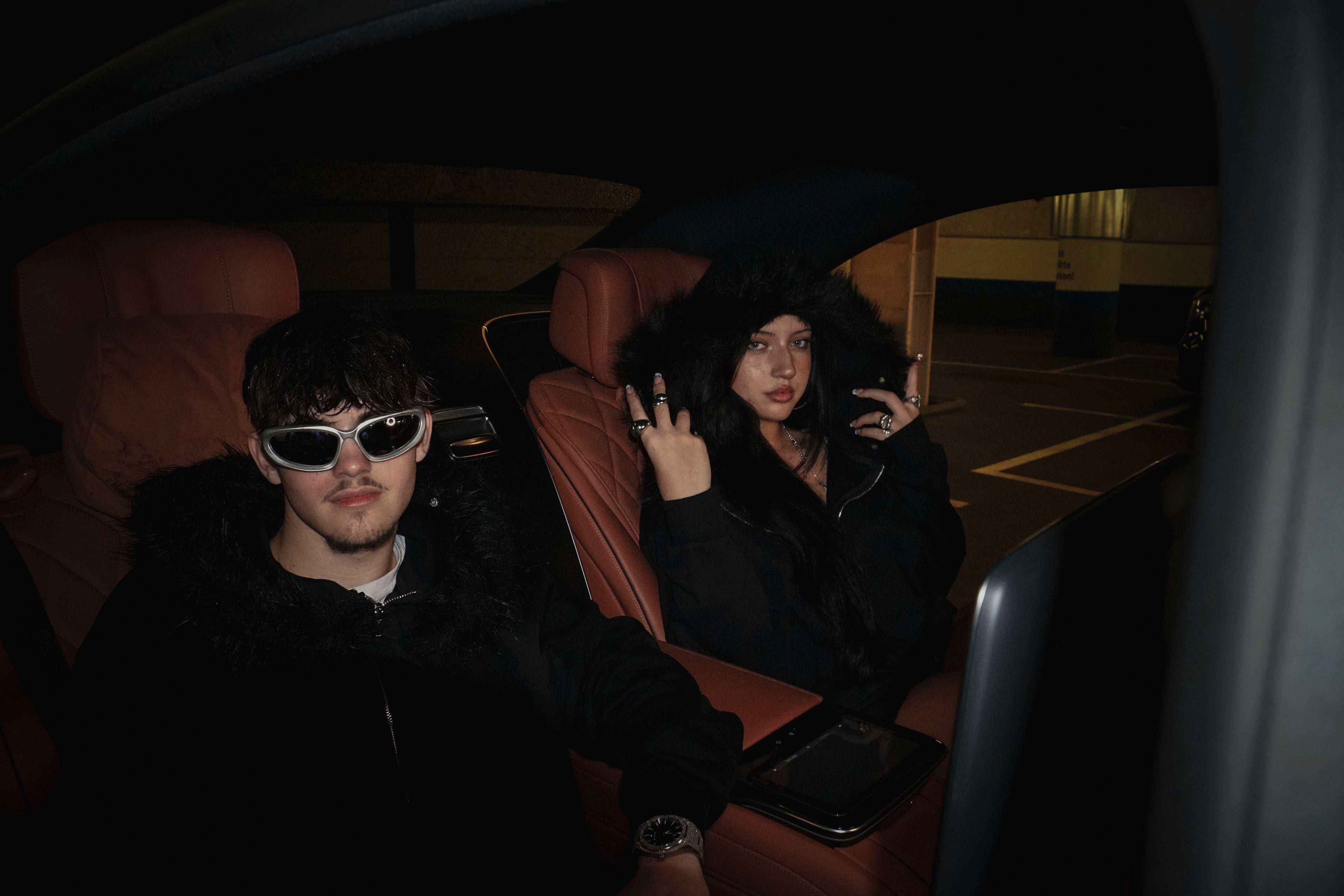 Two People in Fur-Zip Hoodies & Sunglasses, Car at Night