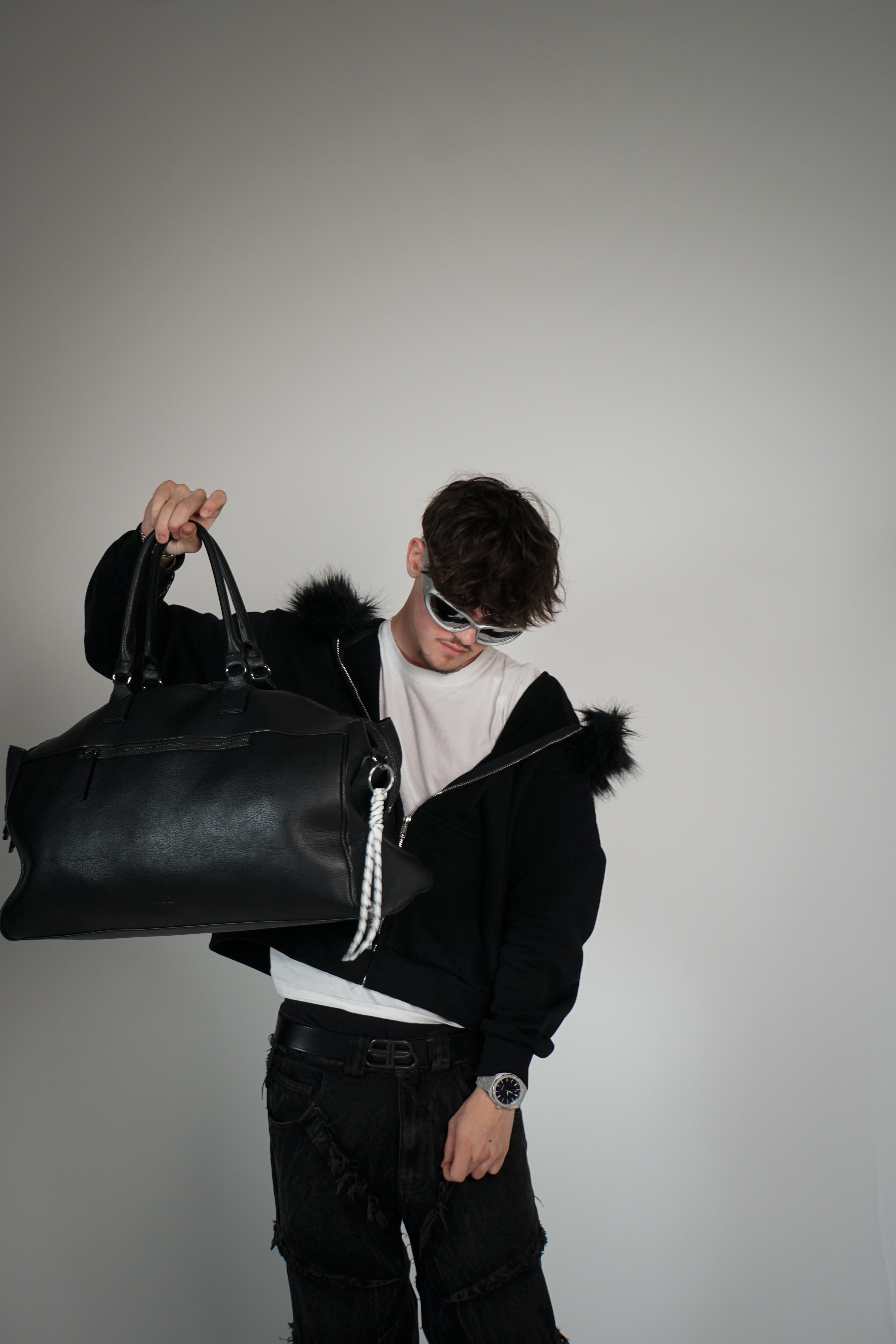 Person holding a large black bag against a plain background