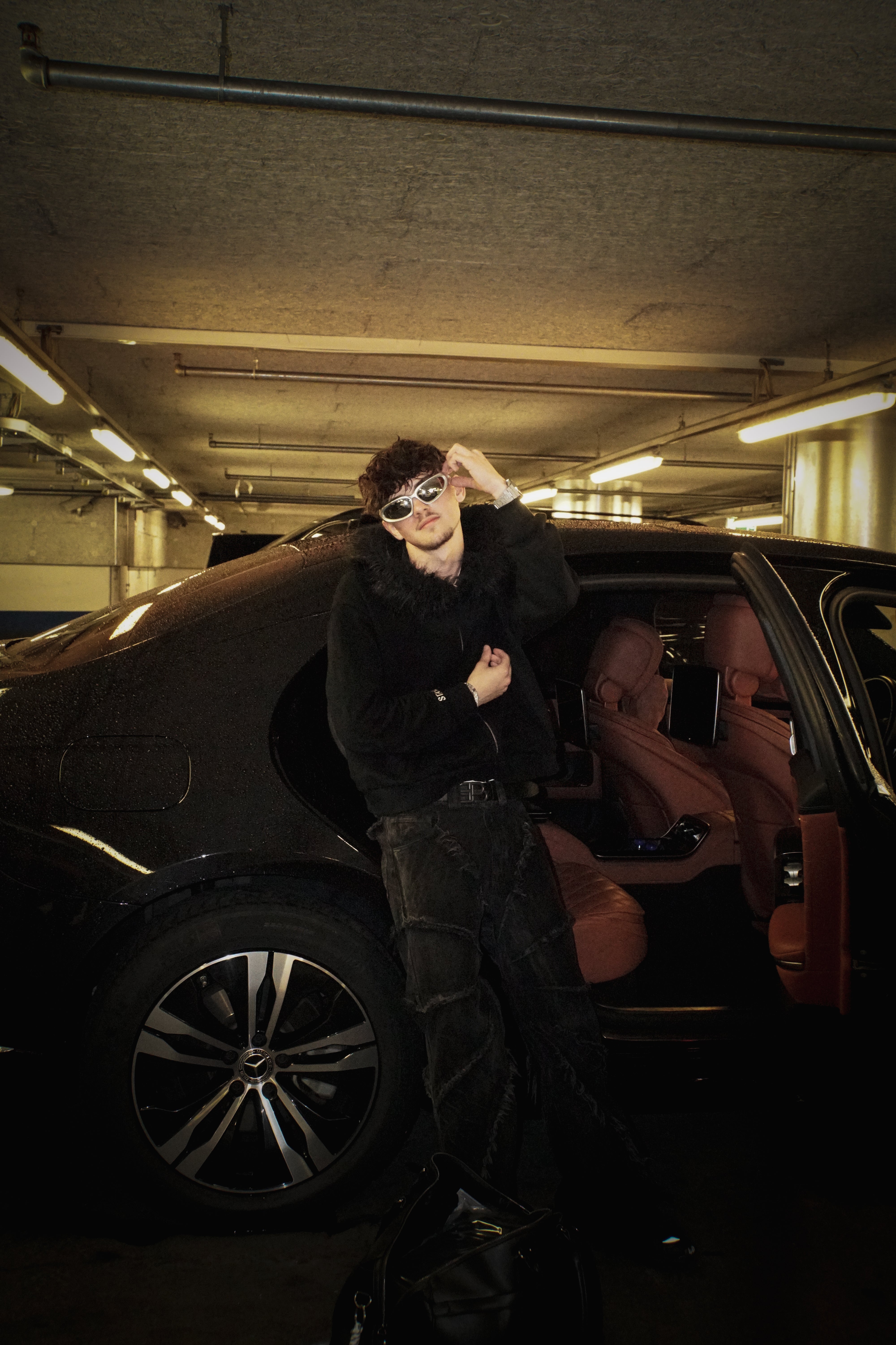 Person standing next to an open car door in a dark parking garage