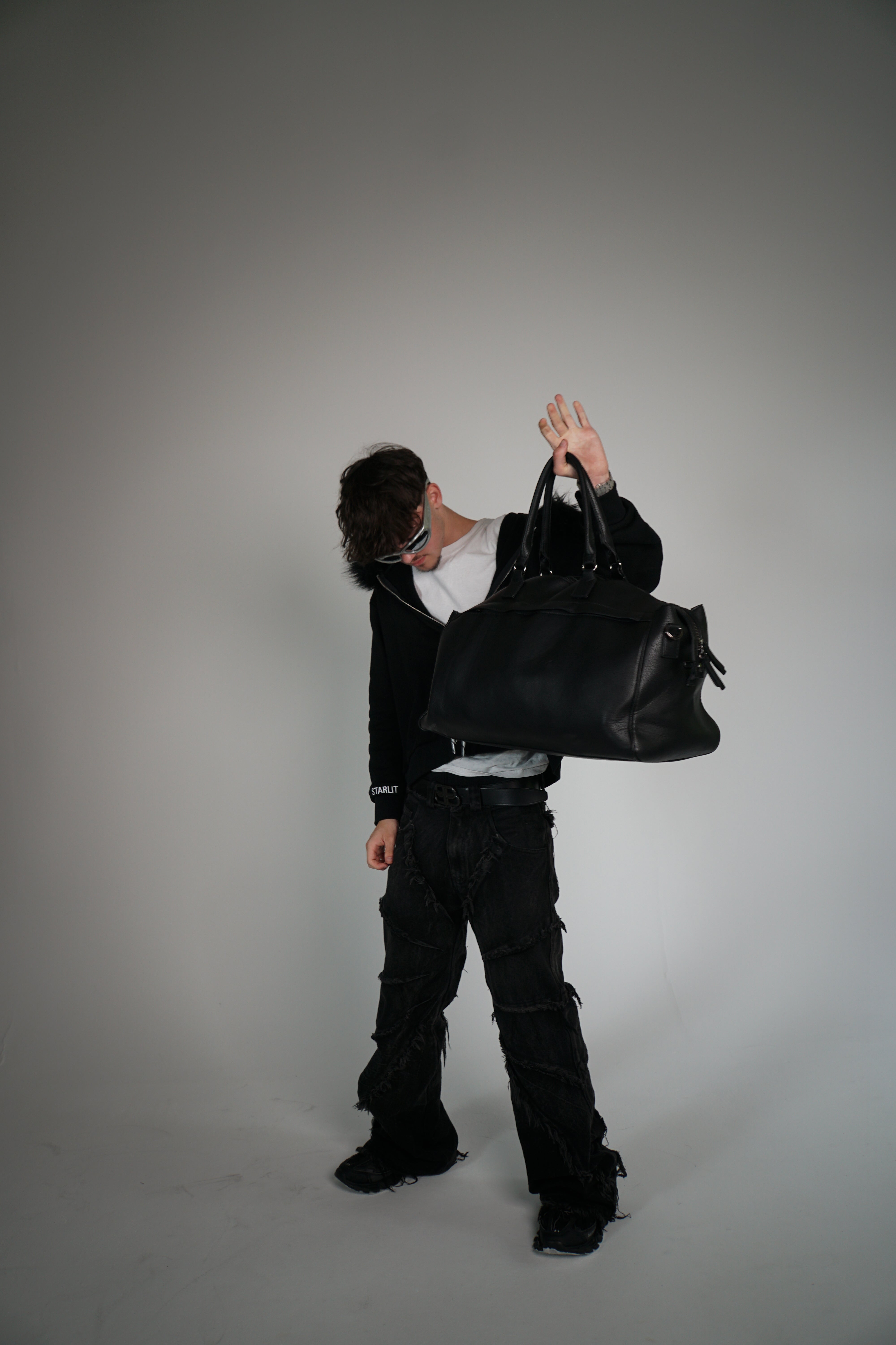Person holding a large black bag against a plain background