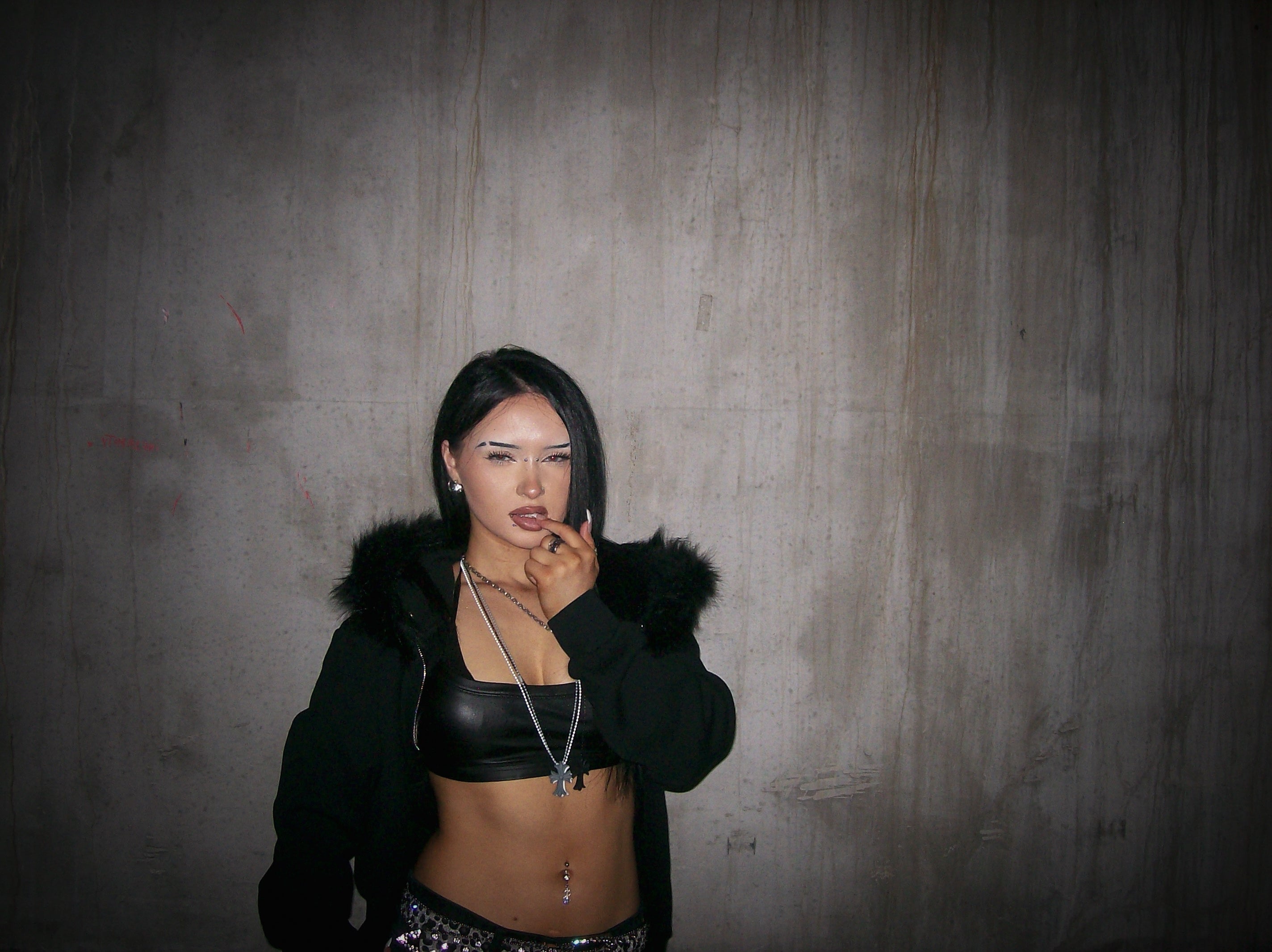 Woman in black jacket and top against a textured gray wall
