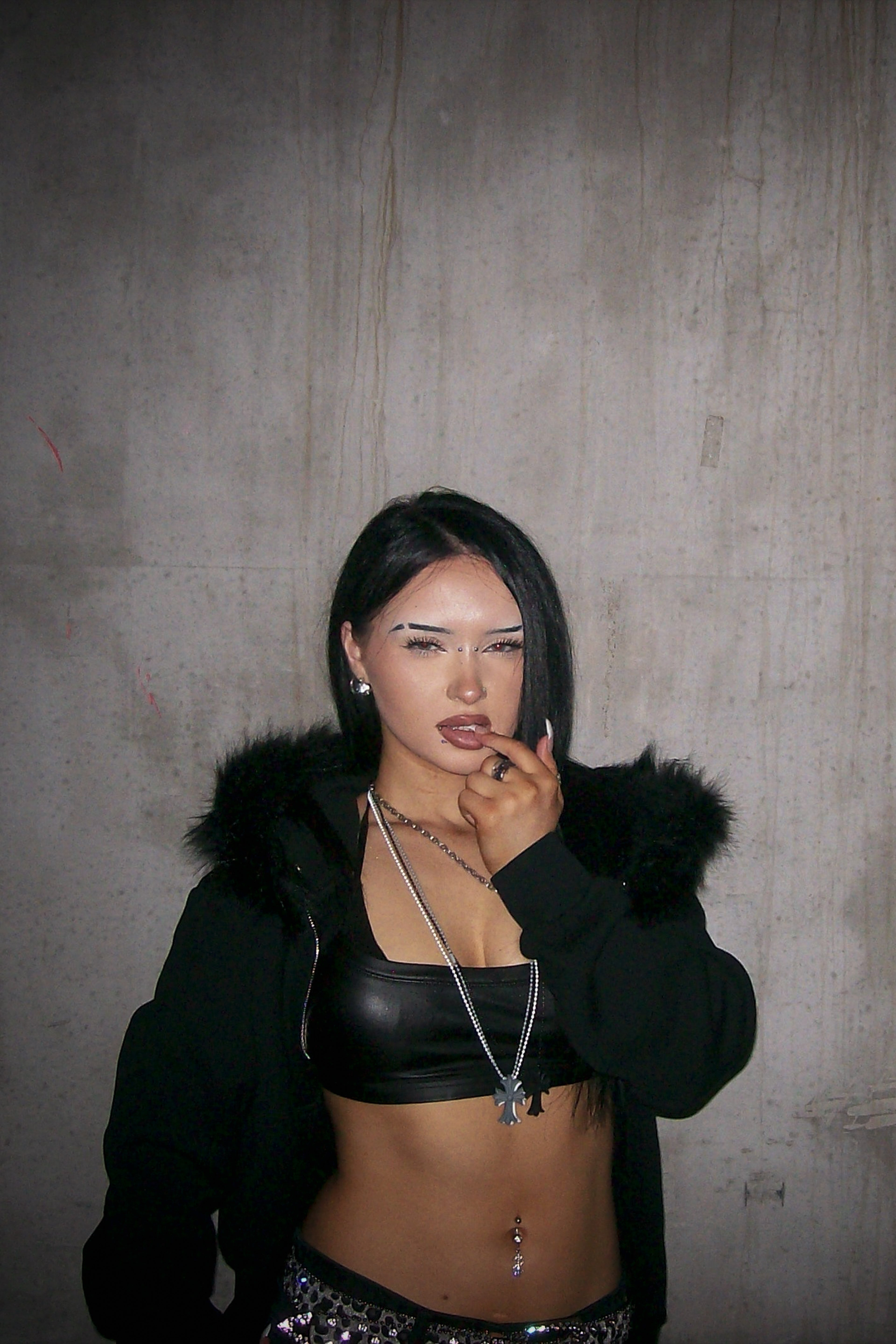 Person wearing a black outfit with fur hood in an industrial setting
