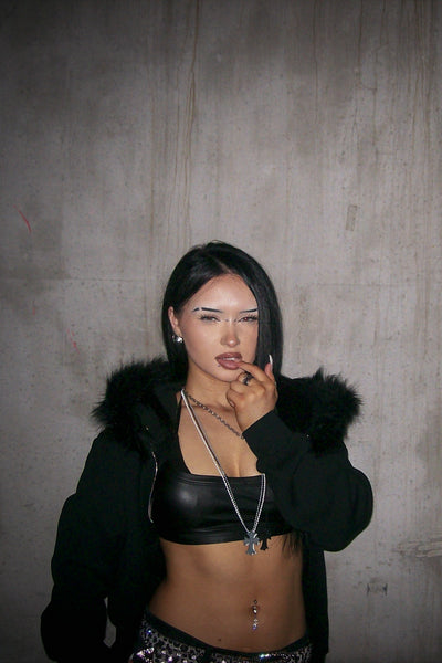 Person wearing a black outfit with fur hood in an industrial setting