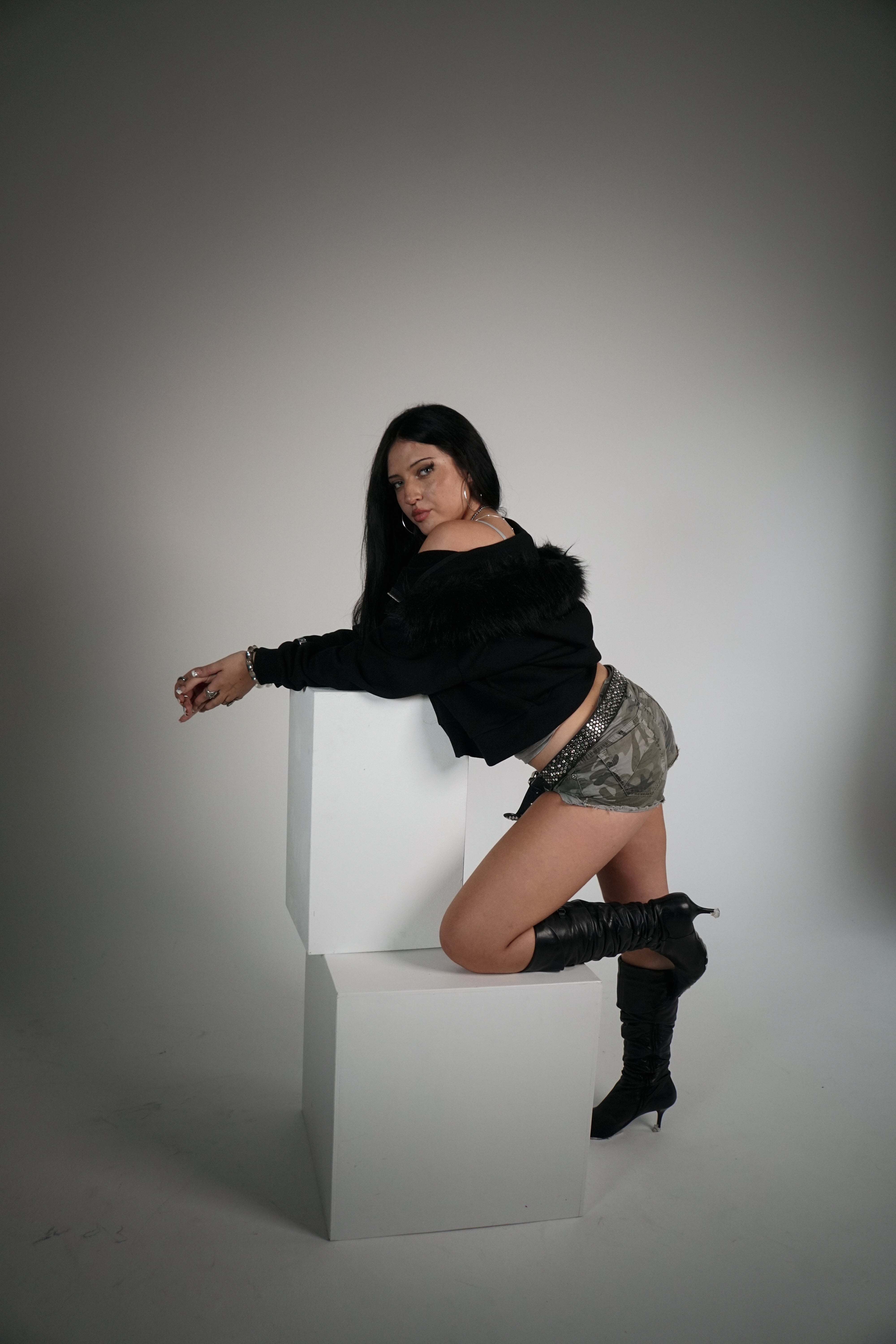 Woman posing on a white cube against a gray background