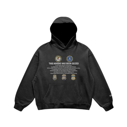 Black hoodie with ‘This Hoodie Has Been Seized’ print and iconic badges, combining bold streetwear and luxury design.